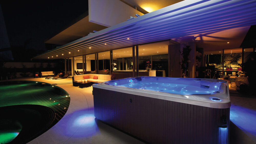 Minipiscina idromassaggio illuminata accanto alla piscina nell’area esterna di un hotel.