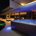 Minipiscina idromassaggio illuminata accanto alla piscina nell’area esterna di un hotel.