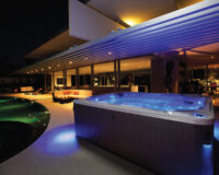 Minipiscina idromassaggio illuminata accanto alla piscina nell’area esterna di un hotel.