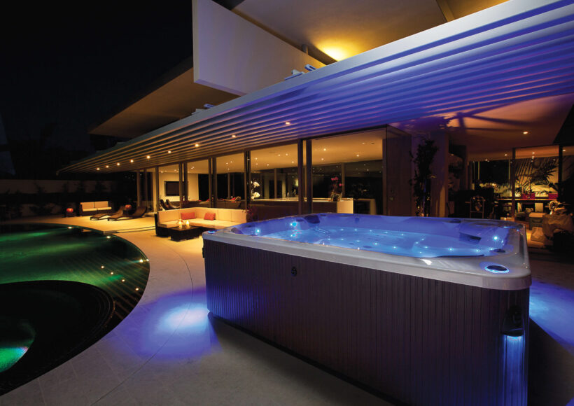 Minipiscina idromassaggio illuminata accanto alla piscina nell’area esterna di un hotel.